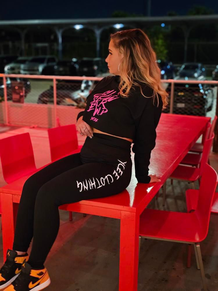 Person wearing a black outfit with text sitting on a red bench at night.