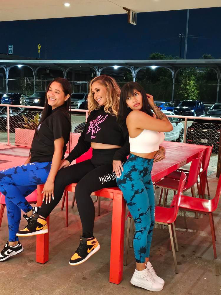 Three women sitting on a red table outdoors at night.