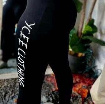 Black leggings with 'YCEE Clothing' text worn by a person, blurred background